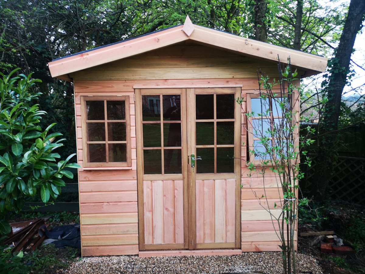 Summerhouse with glazed doors and apex roof in garden setting